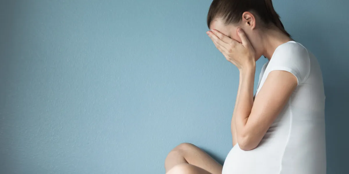 stressed pregnant woman against blue background stressed pregnant woman against blue background