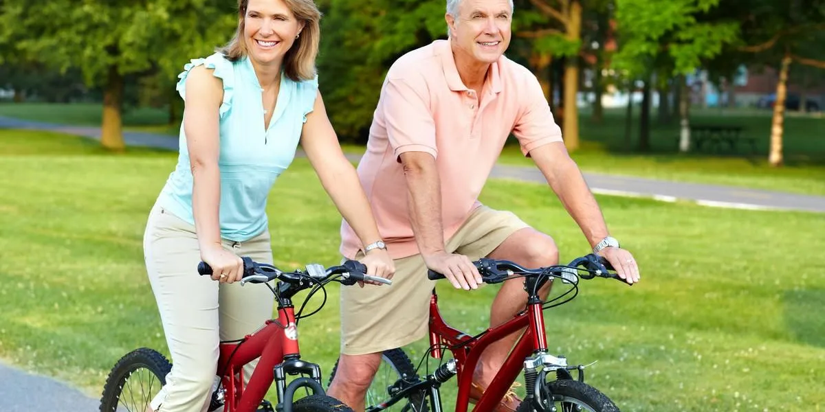 happy elderly senior couple cycling in park