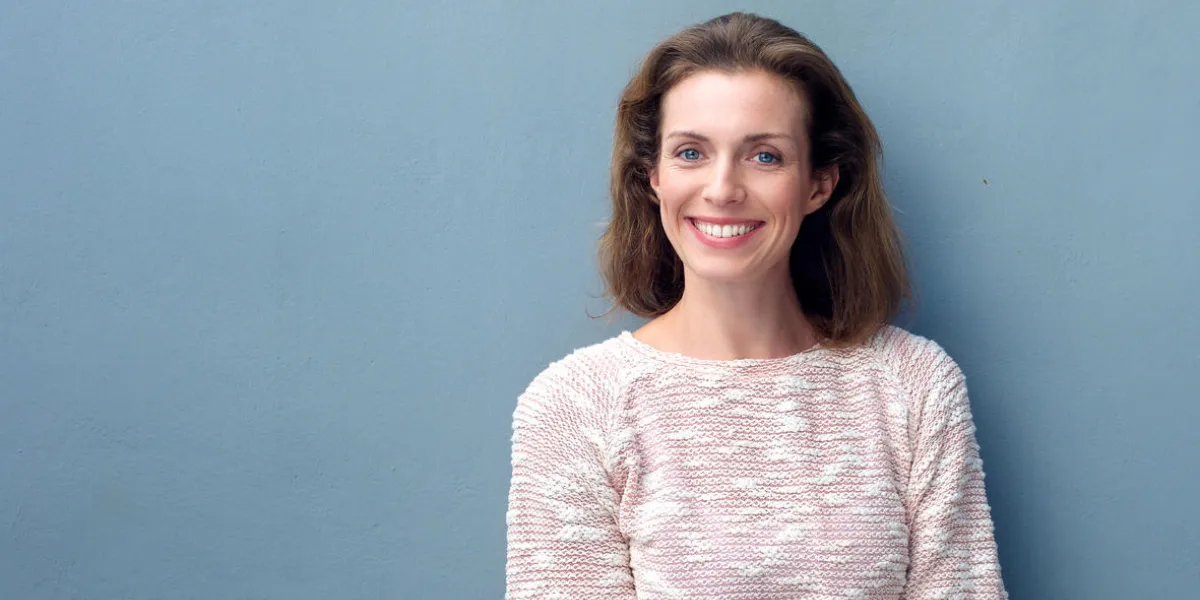 portrait of a beautiful mid adult woman smiling on blue background