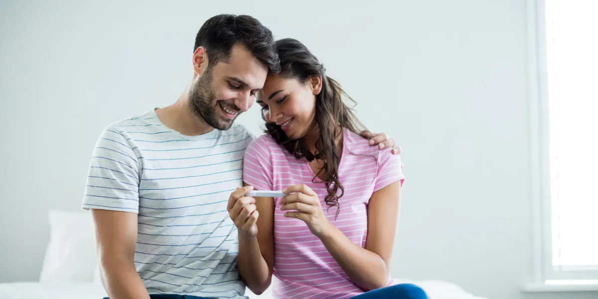 joyful couple finding out results of a pregnancy test in the bedroom at home
