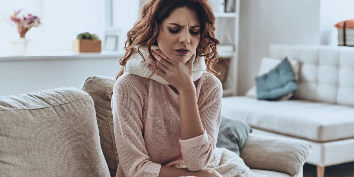 sick young women covered with blanket coughing while sitting on the sofa at home sick young women covered with blanket coughing while sitting on the sofa at home