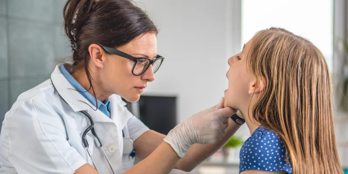 female doctor checking little girl's throat at medical office