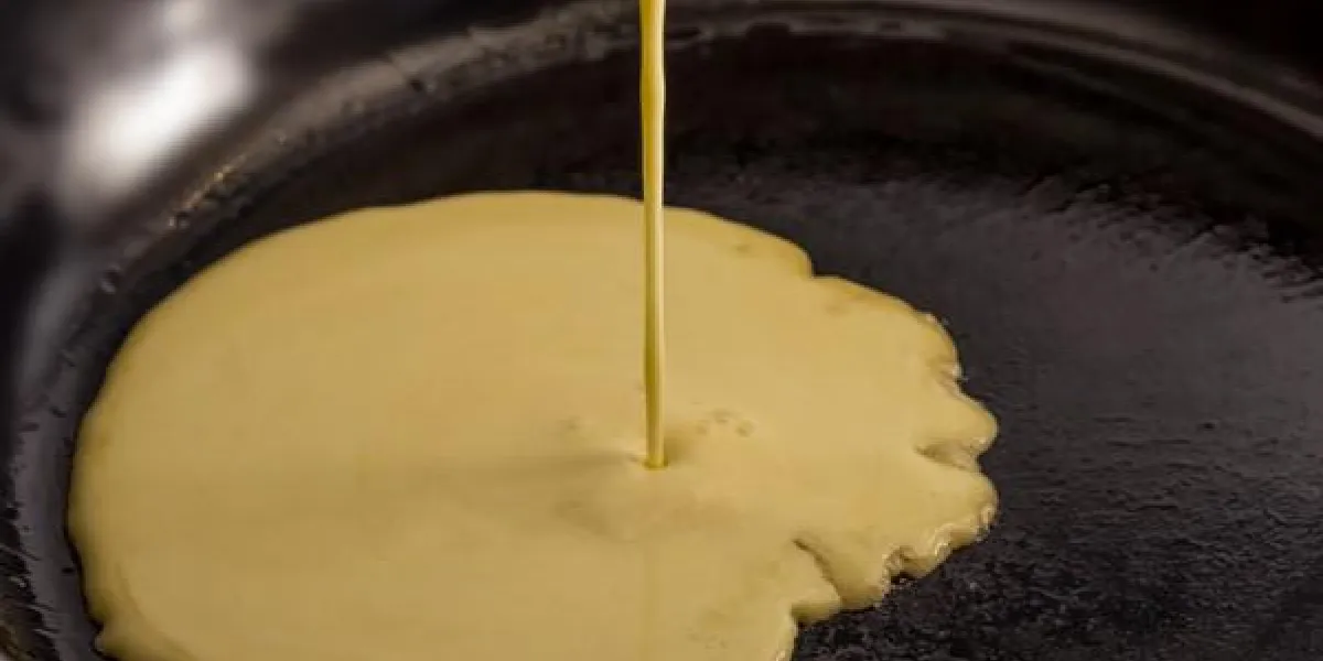 pâte à crêpes verser dans une poêle noire sur un poêle pâte à crêpes verser dans une poêle noire sur un poêle