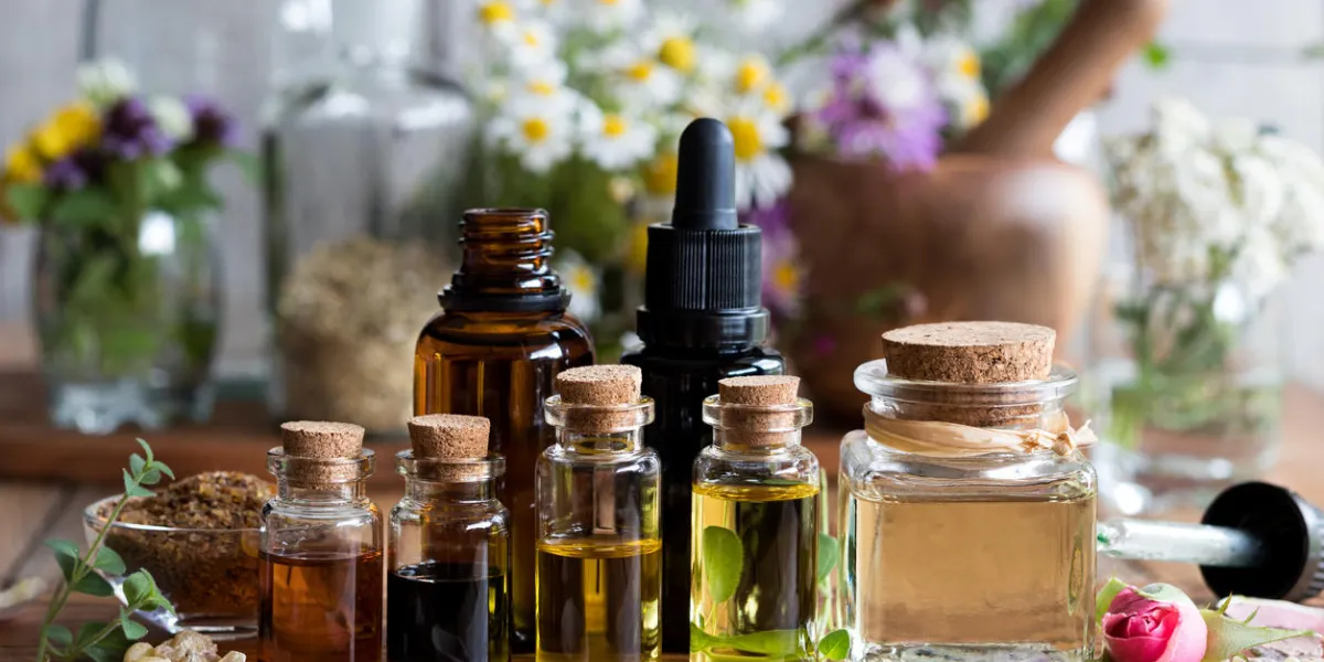 selection of essential oils with various herbs and flowers in the background selection of essential oils with various herbs and flowers in the background