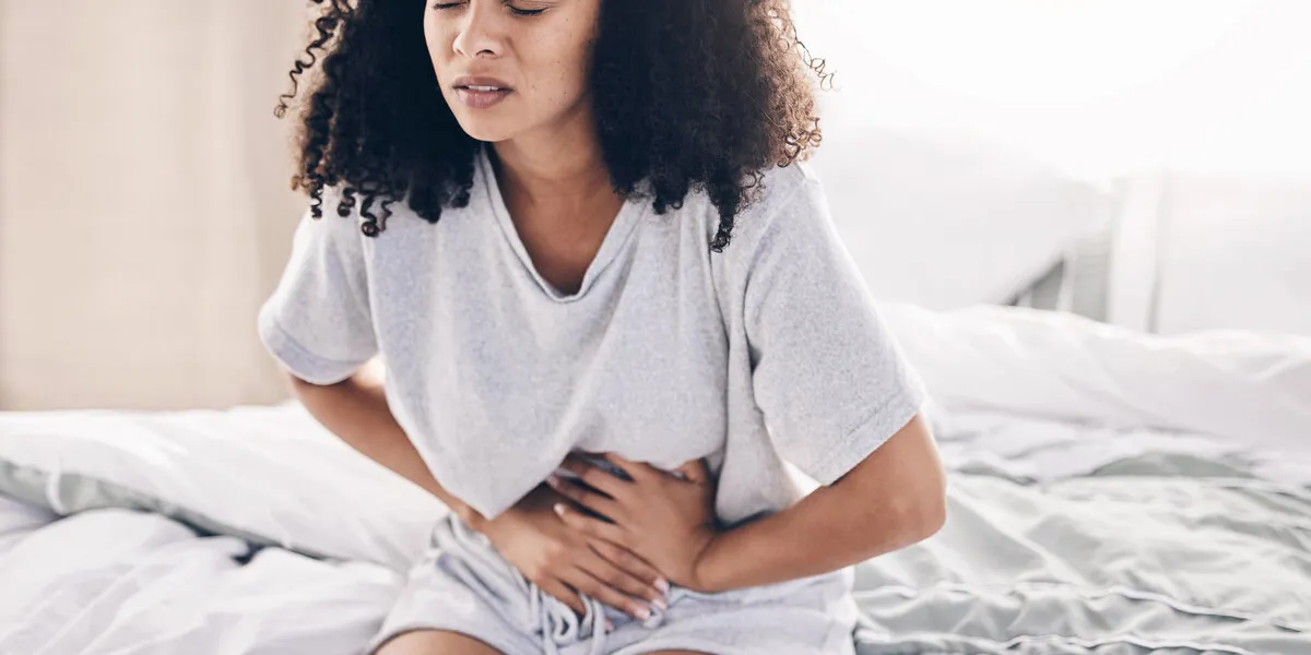 abdomen pain, period and black woman in bed with abdominal cramps, menstruation and stomach ache health, medical emergency and girl with digestion problem, pms crisis and endometriosis in bedroom