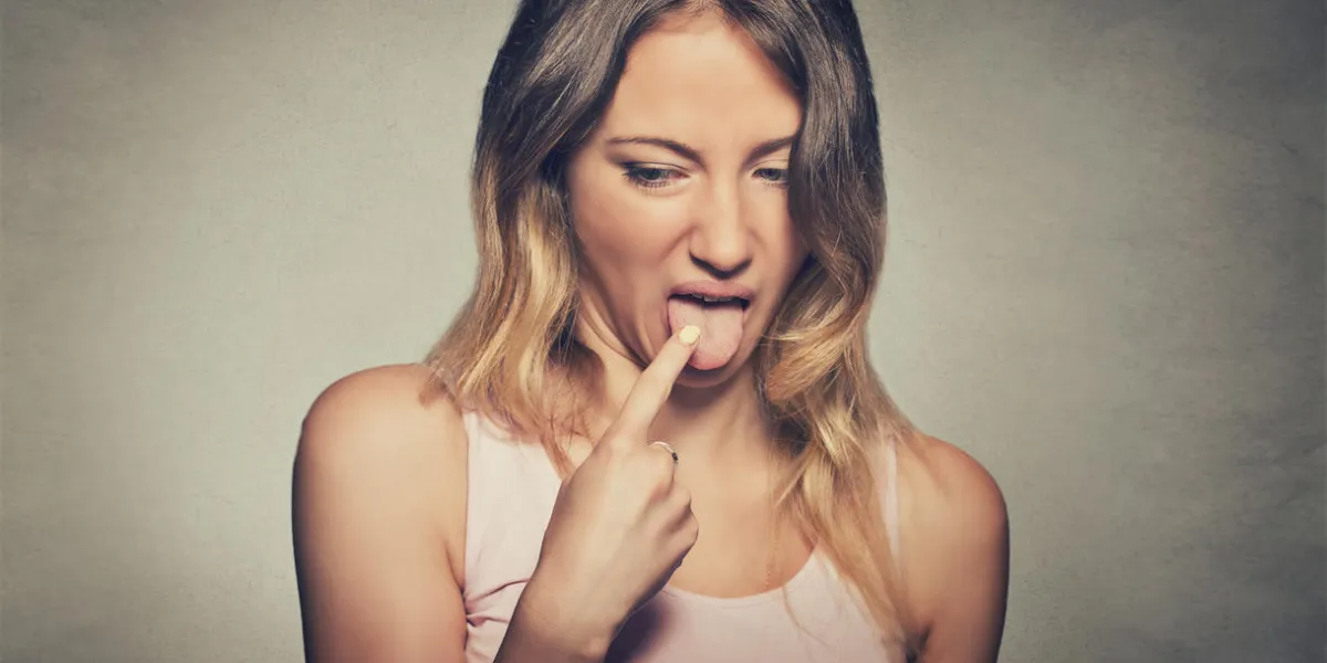 closeup portrait young woman, annoyed, frustrated fed up sticking her finger in her throat showing she is about to throw up isolated on gray wall background