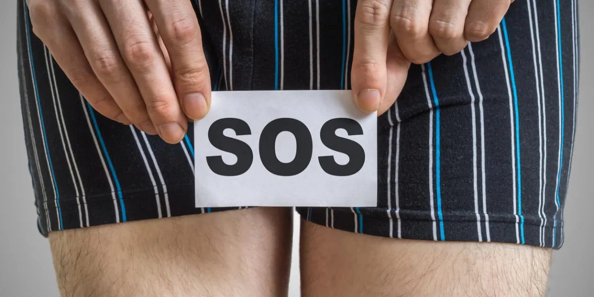 urinary or prostate problems concept young man holds paper with sos above crotch