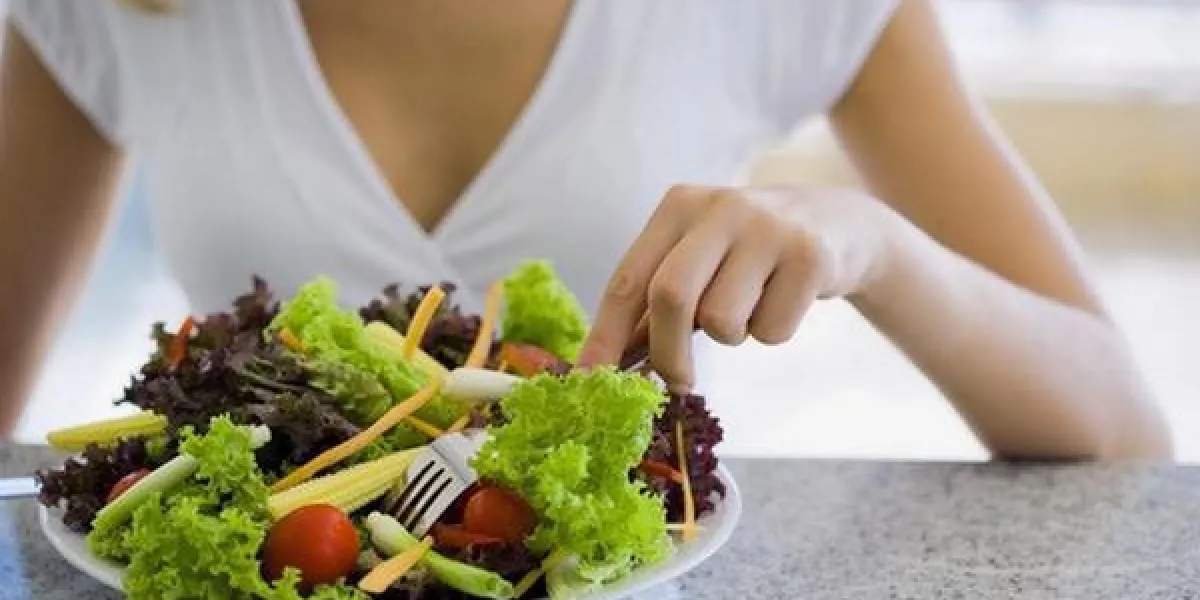 gros plan d'une assiette de crudités, femme tenant une fourchette