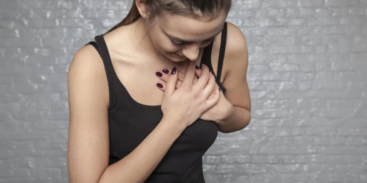 a young woman is holding her chest, possible heart attack or other heart disease a young woman is holding her chest, possible heart attack or other heart disease