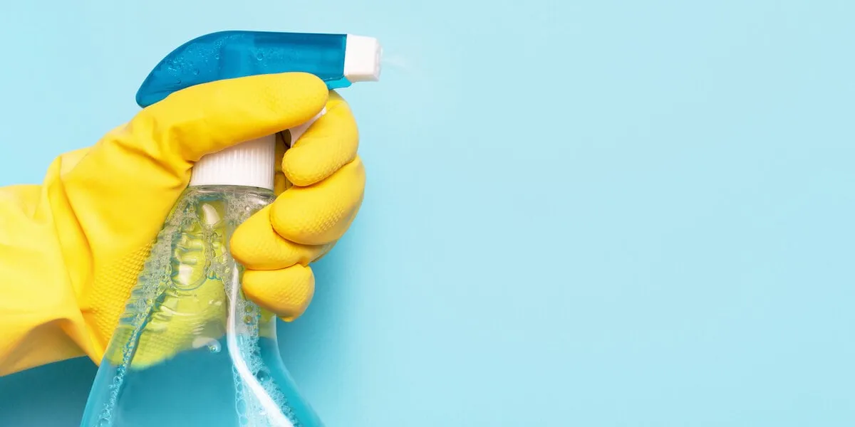 female hand in glove holds window spray on blue background, a spring cleaning concept female hand in glove holds window spray on blue background, a spring cleaning concept