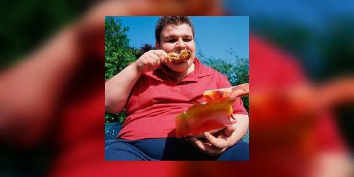 homme adolescent en surpoids avec des cheveux hérissés mangeant un pilon de poulet homme adolescent en surpoids avec des cheveux hérissés mangeant un pilon de poulet