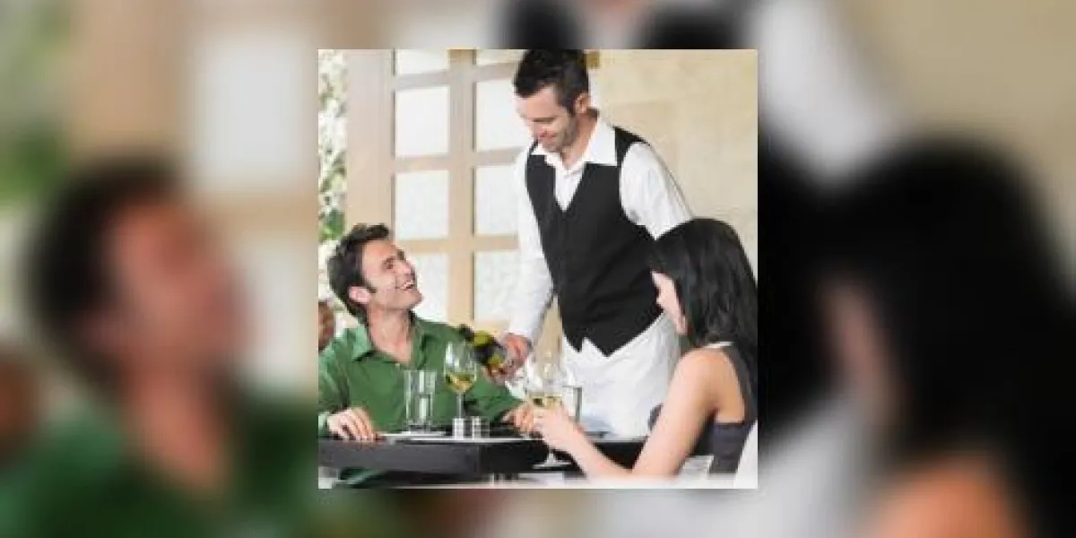 serveur servant du vin au jeune couple au restaurant en plein air