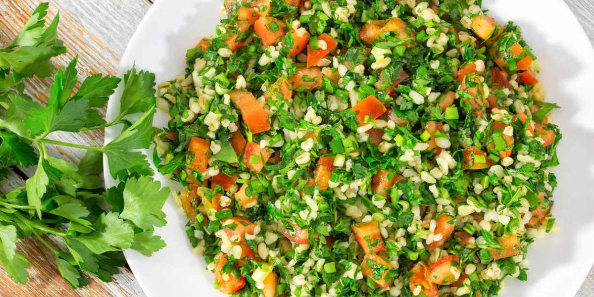 bulgur wheat gluten free vegetarian parsley,mint, spring onion, tomato salad, drizzled with lemon juice and olive oil on white dish on peeling paint table, authentic recipe,close-up, view from above bulgur wheat gluten free vegetarian parsley,mint, spring onion, tomato salad, drizzled with lemon juice and olive oil on white dish on peeling paint table, authentic recipe,close-up, view from above