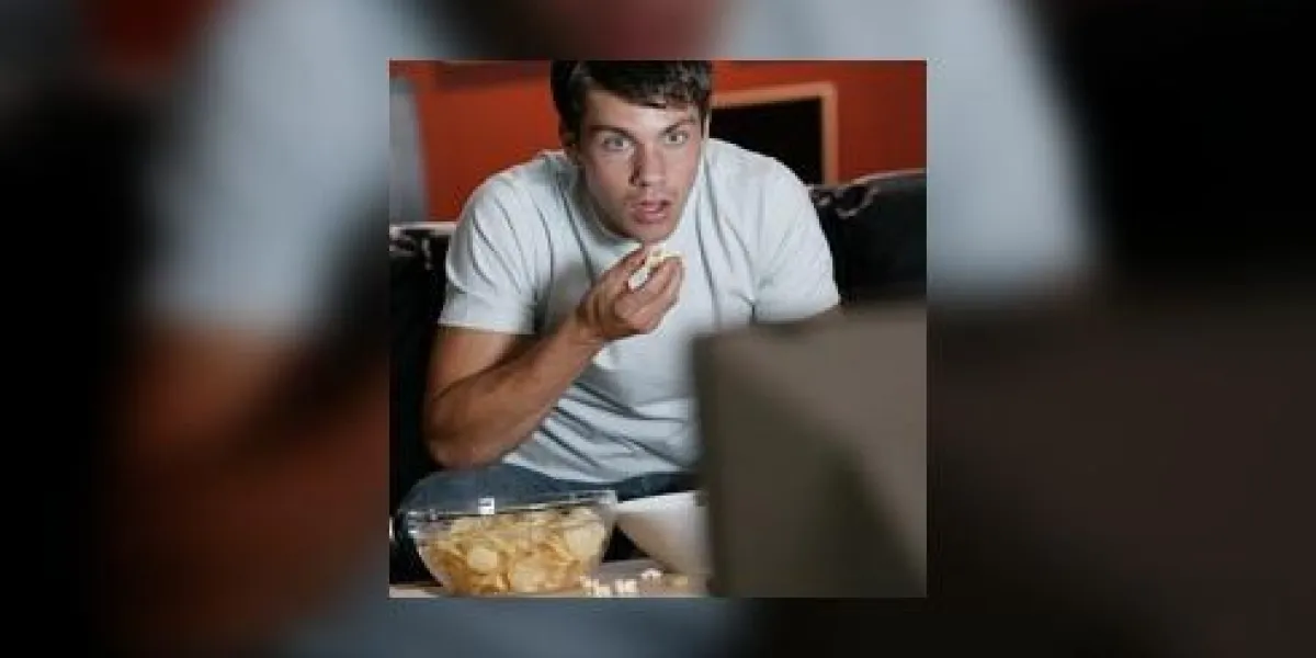 homme étonné manger et regarder la télévision