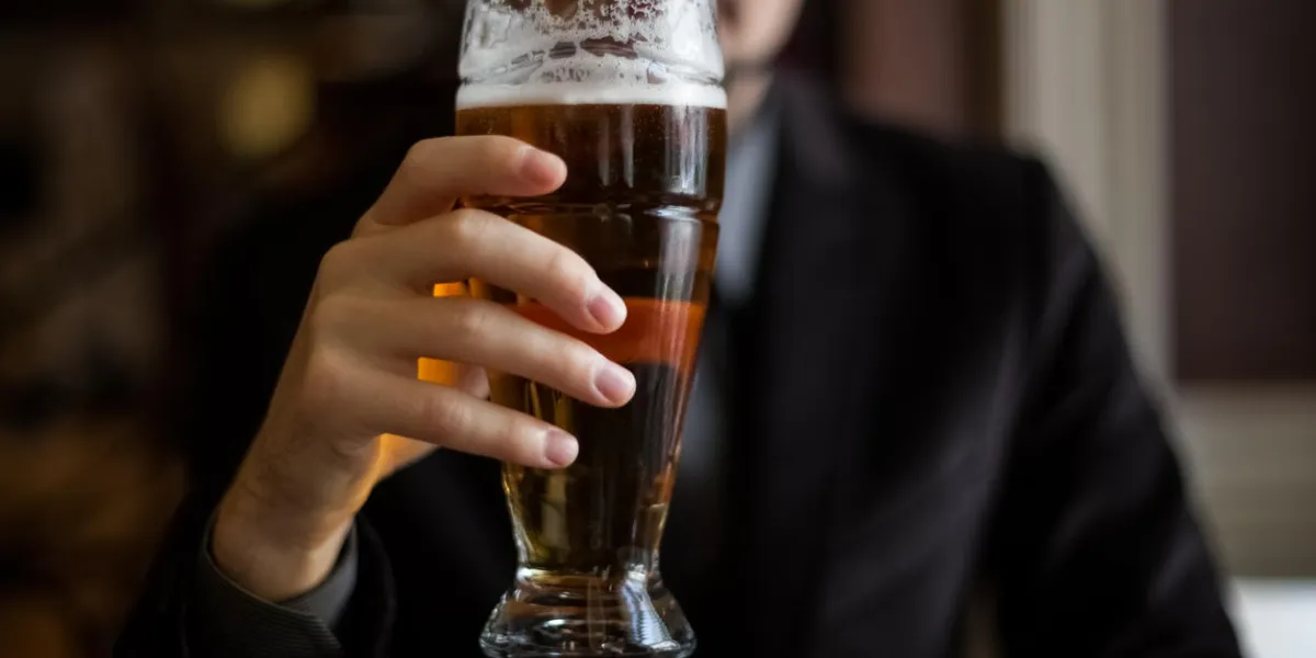 gros plan d'un homme tenant une tasse de bière