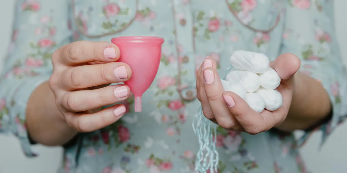 woman hands holding tampons and menstrual cup comparation of different methods of female intimate hygiene