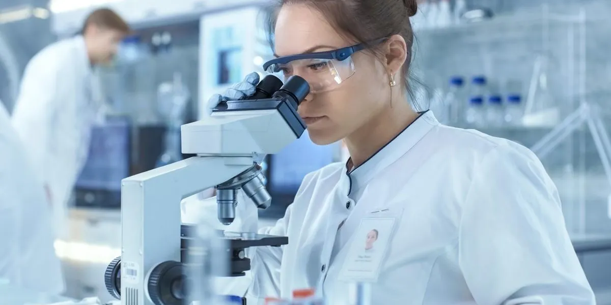 medical research scientists looking at samples under microscope she works in a bright modern laboratory