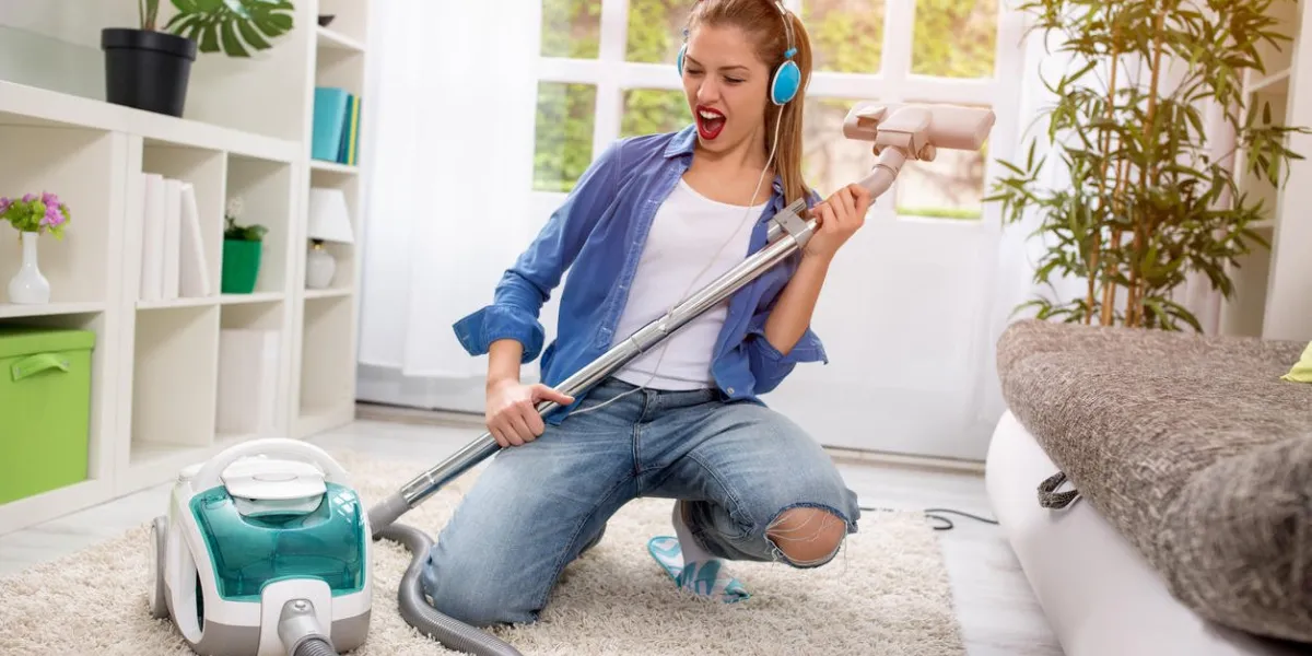 smiling excited young housewife havig fun with vacuum cleaner