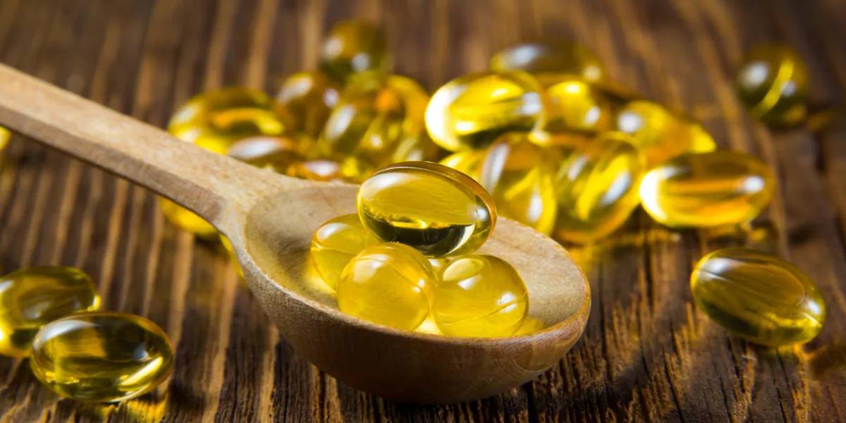 cod-liver oil, omega3, vitamin d capsules on wooden spoon