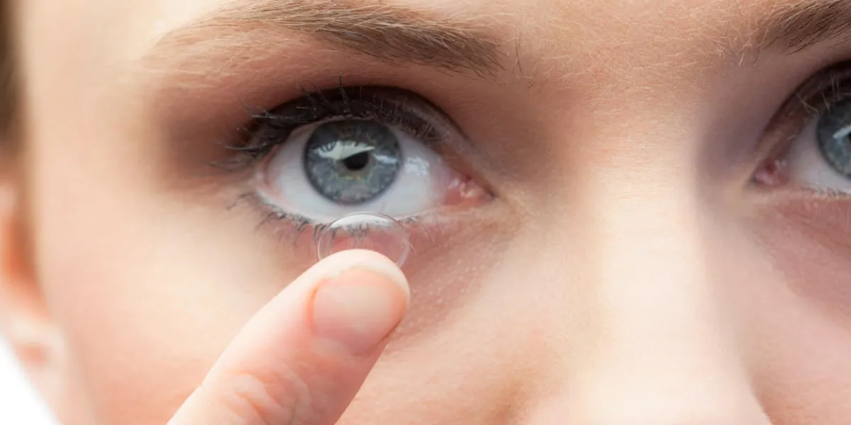 extreme close up on gorgeous model applying contact lens on her blue eyes