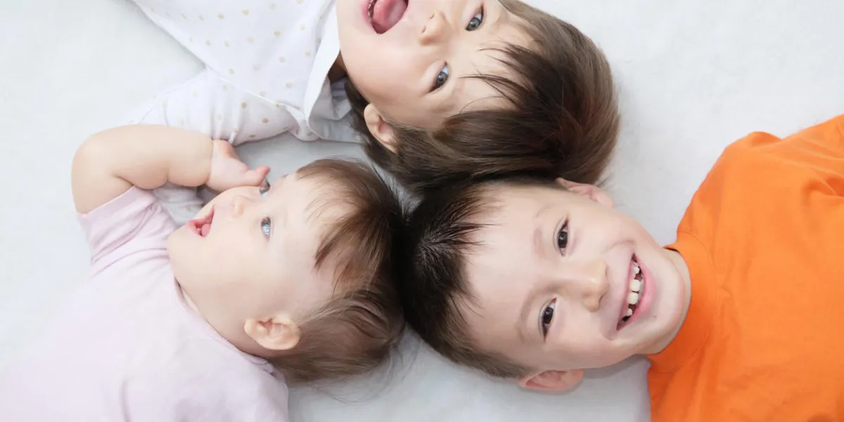 happy kids, three laughing children different ages lying, portrait of boy, little girl and baby girl, happiness in childhood of siblings, living in big family with three children