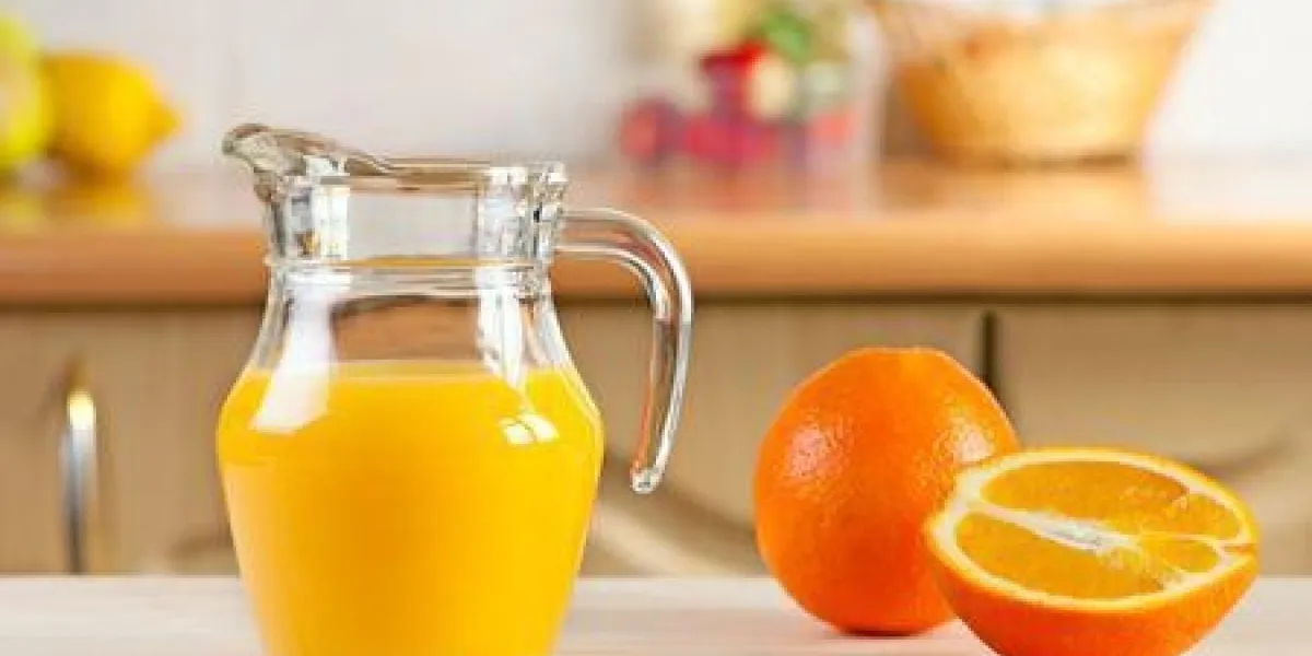 pichet en verre de jus d'orange fraîchement pressé sur un dessus de table avec une orange entière et coupée en deux pichet en verre de jus d'orange fraîchement pressé sur un dessus de table avec une orange entière et coupée en deux