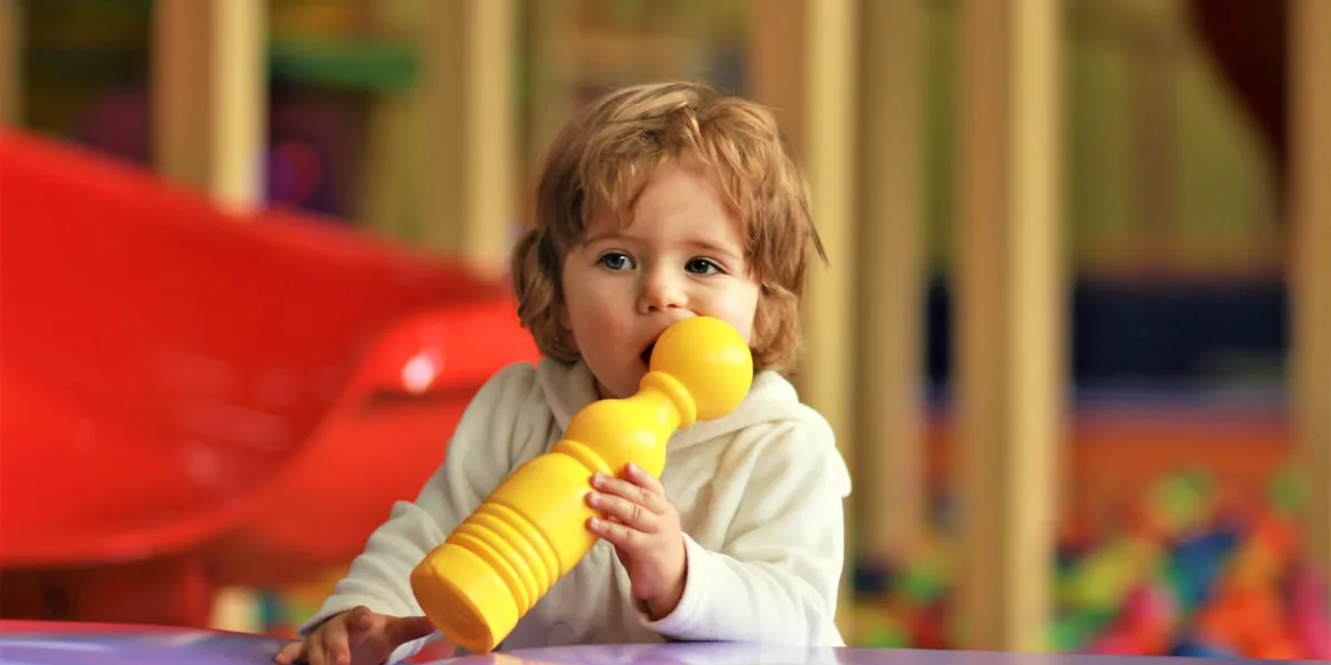 cute little girl on the playground teething on a toy