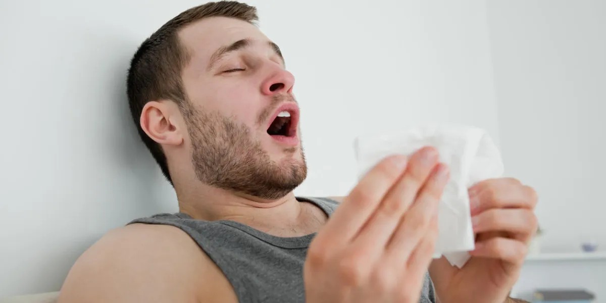 sick man sneezing in his bedroom