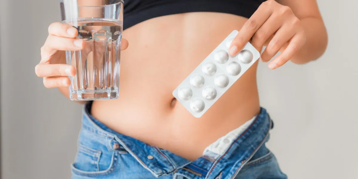 close up portrait of woman showing diet pills and a glass of water, healthcare and diet concept