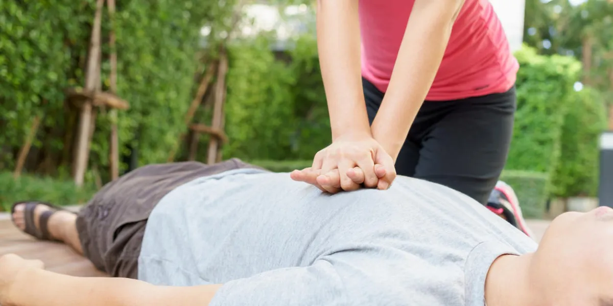 woman giving cardiopulmonary resuscitation (cpr) to a man at public park