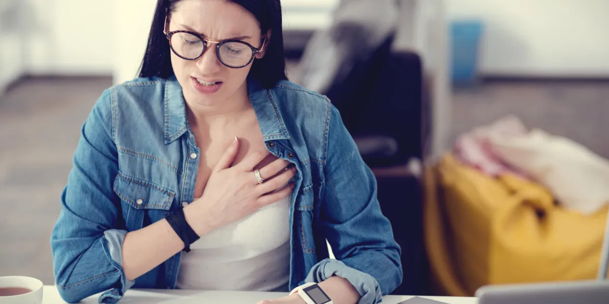 pain in the chest unhappy pleasant young woman sitting at the table and working while feeling unwell