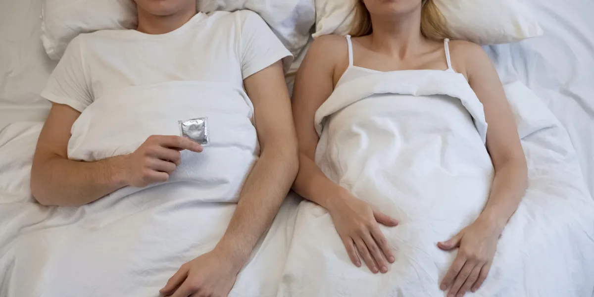 young man holding condom suggesting intimacy to girlfriend, responsible attitude young man holding condom suggesting intimacy to girlfriend, responsible attitude
