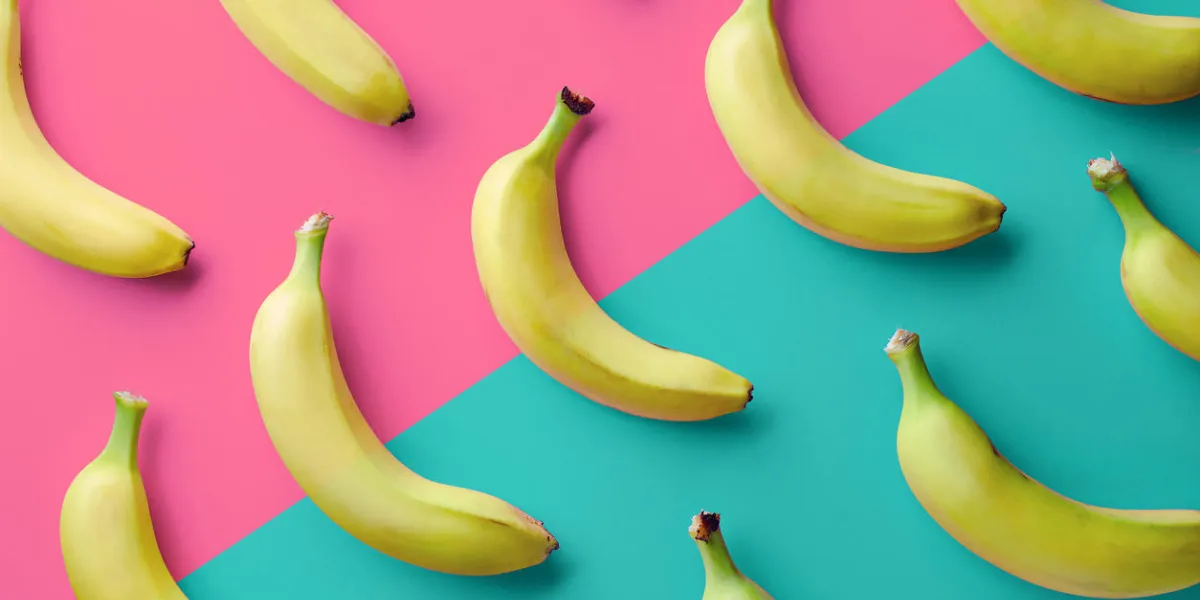 colorful fruit pattern of fresh yellow bananas on pink and blue background from top view colorful fruit pattern of fresh yellow bananas on pink and blue background from top view