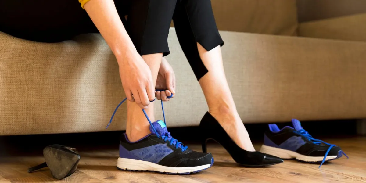 woman changing high heels, office shoes after working day while sitting on the couch, ready to take a walk or run
