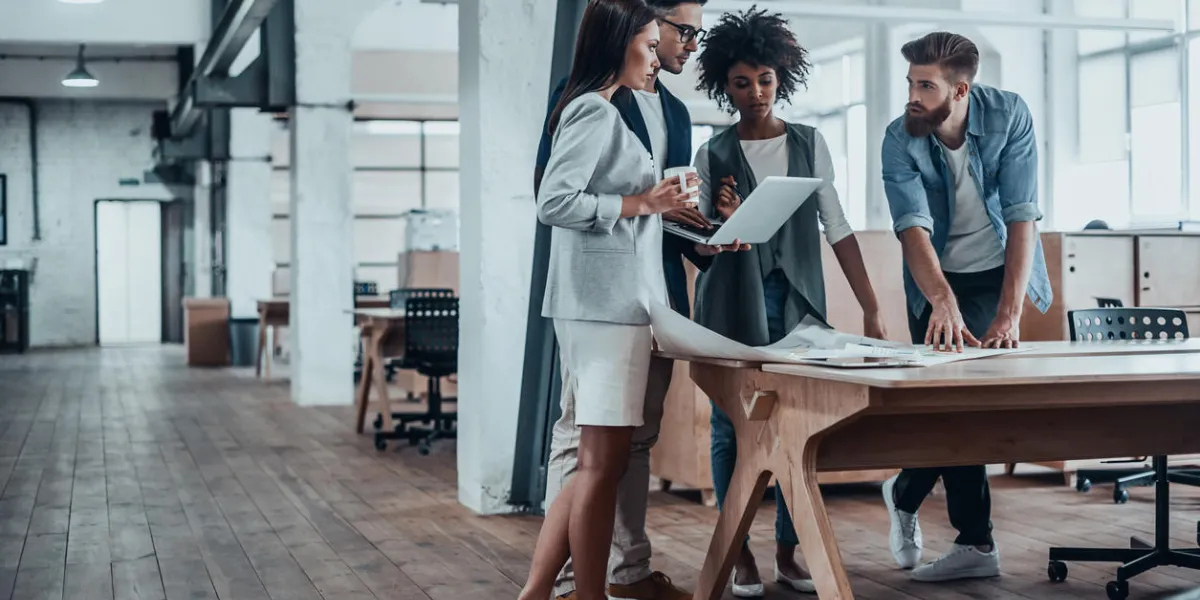 group of young business people working together in creative office while standing near the wooden desk group of young business people working together in creative office while standing near the wooden desk