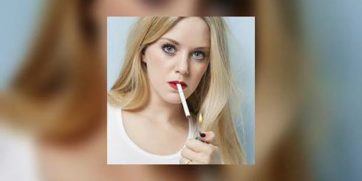 portrait de jeune femme blonde allumant la cigarette sur fond bleu clair portrait de jeune femme blonde allumant la cigarette sur fond bleu clair