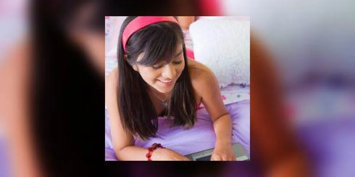 adolescente travaillant sur un ordinateur portable avec une jeune femme allongée à côté d'elle sur le lit adolescente travaillant sur un ordinateur portable avec une jeune femme allongée à côté d'elle sur le lit