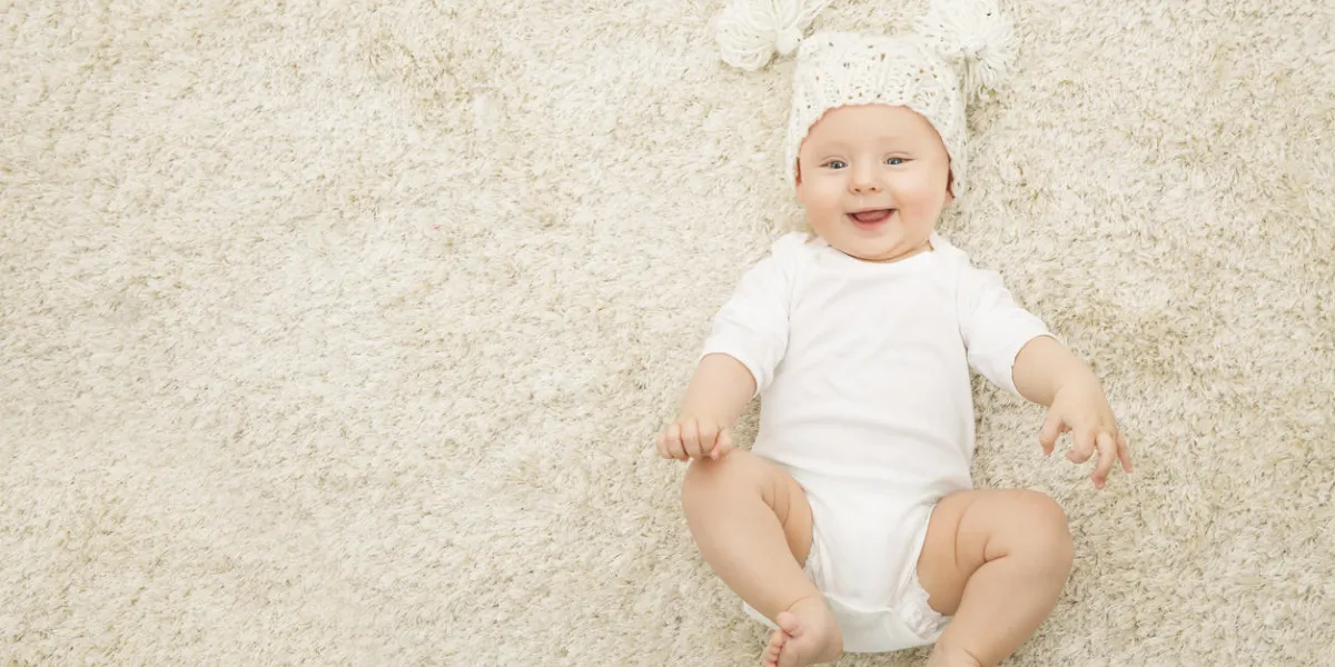 happy baby in hat and diaper lying on carpet background, smiling infant kid boy in white clothing, child six months old happy baby in hat and diaper lying on carpet background, smiling infant kid boy in white clothing, child six months old