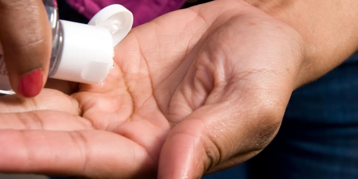 an african american woman applying hand sanitizer an african american woman applying hand sanitizer