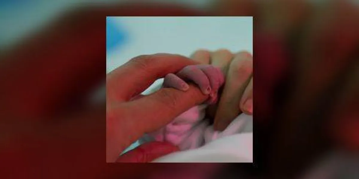 nouveau-né attrape le doigt de son père