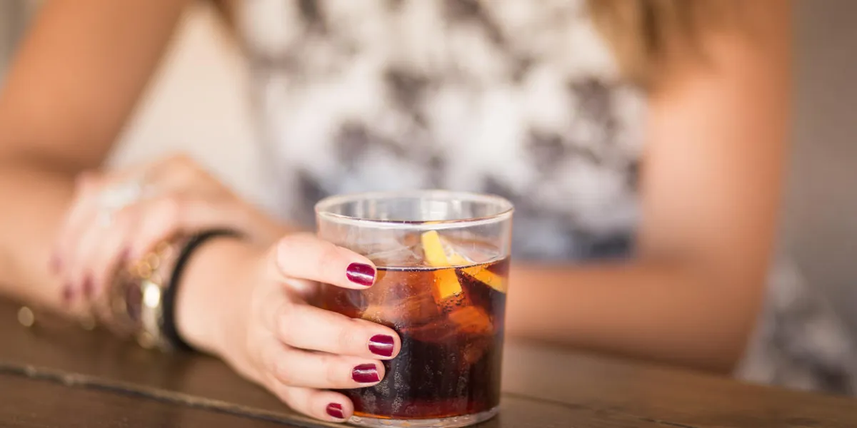 attractive young woman seated at a terrace taking soda coke
