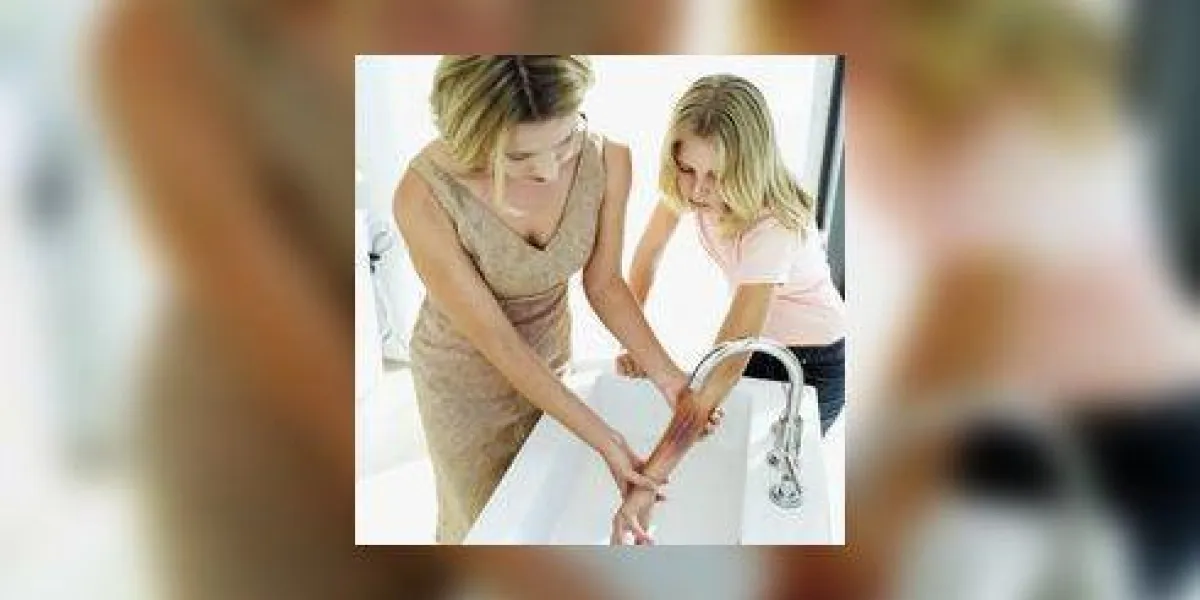 femme tenant la main brûlée d'une fille sous un robinet d'eau