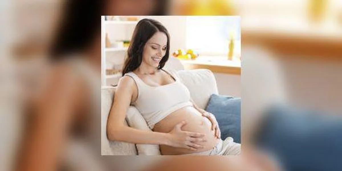 elle va être une maman bientôt belle jeune femme enceinte toucher son ventre et souriant tout en étant assis sur le canapé