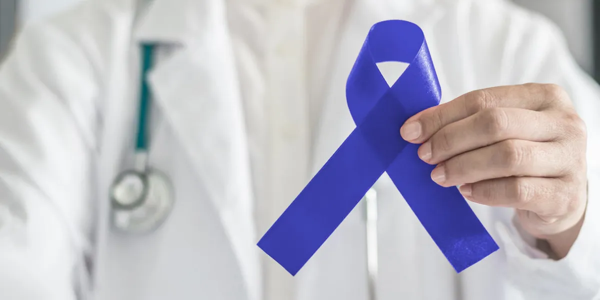 dark blue ribbon for colon - colorectal cancer awareness on medical doctor's hand support