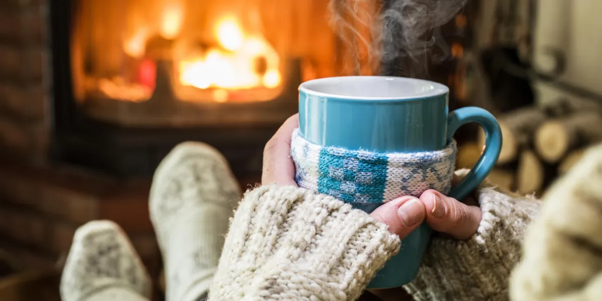 warming and relaxing near fireplace with a cup of hot drink warming and relaxing near fireplace with a cup of hot drink