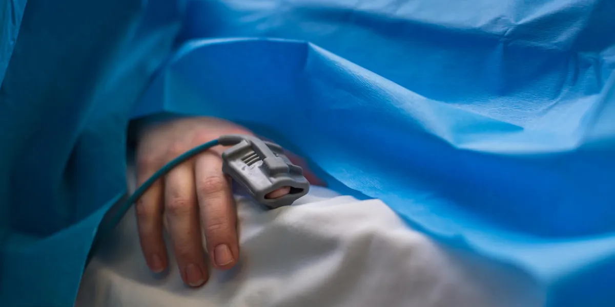 detail of a hand of a patient being monitored during surgery - vital functions of the body are being closely watched by the anaesthesiologist (color toned image, shallow dof)