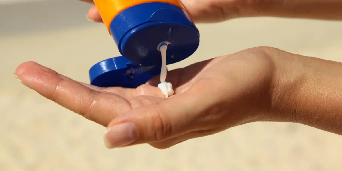 woman holding and applying suntan lotion on a beach