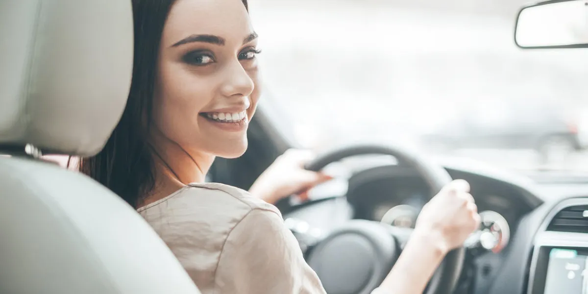 rear view of attractive young woman in casual wear looking over her shoulder while driving a car