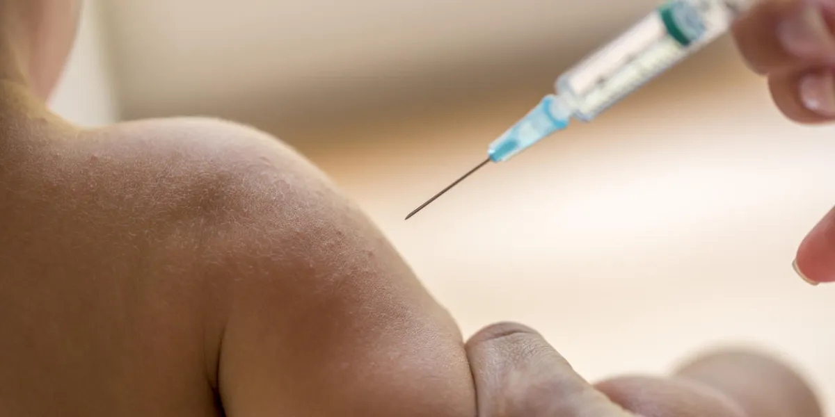 doctor injecting a young child with a vaccination or antibiotic in a small disposable hypodermic syringe, close up of the kids arm and needle