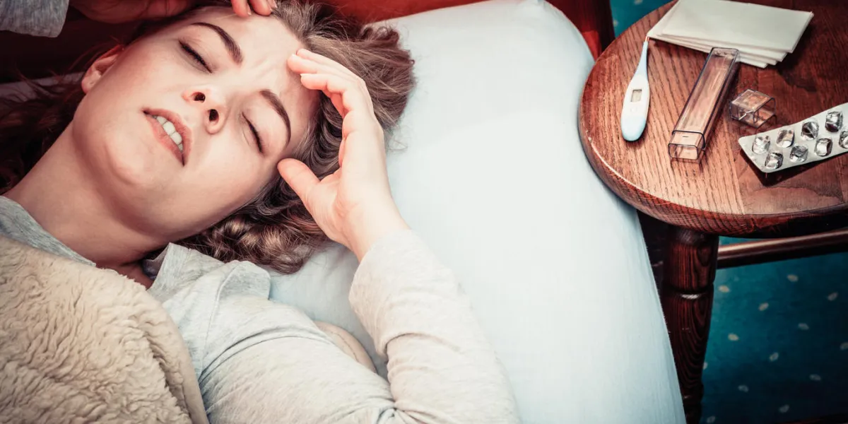 sick woman suffering from headache pain ill girl laying in bed caught cold thermometer and pills on table